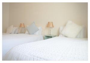 Duas camas brancas sentadas uma ao lado da outra num quarto em no 3 Leitrim Road em Carrick on Shannon mais 3 fotografias