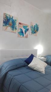 een blauw bed in een slaapkamer met schilderijen aan de muur bij Sweety House in San Giovanni Gemini