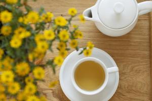 una taza de café sobre una mesa con flores amarillas en Landhotel Pension Haus Sonneck en Manderscheid