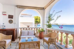 a porch with chairs and a table and a view of the ocean at Villa Ponente in Spetses