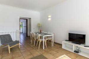 uma sala de jantar com uma mesa e cadeiras e uma televisão em FLH Praia da Luz Apartment with Pool em Alagoas