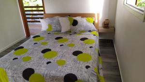 uma cama com um edredão amarelo e verde e almofadas em APPARTEMENT MILO 1 em Bouillante