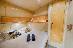 - un lit dans une petite chambre avec des chaussons bleus dans l'établissement HEBERGEMENTS BATEAUX A QUAI, à Porquerolles