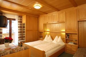 1 dormitorio con 1 cama y TV. en Garni Edera, en Corvara in Badia