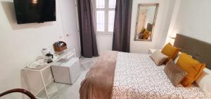 1 dormitorio con 1 cama y TV en la pared en Fan Rooms Duquesa en Málaga
