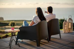 Ein Mann und eine Frau, die auf einer Terrasse auf Stühlen sitzen in der Unterkunft Villa Mariense in Vila do Porto