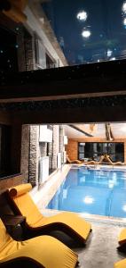 a large swimming pool with yellow chairs in a building at Hotel Superski in Cavnic