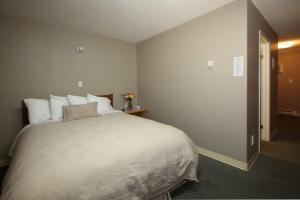 a bedroom with a large bed with white sheets and pillows at Anchor Riverfront Motel in Sicamous