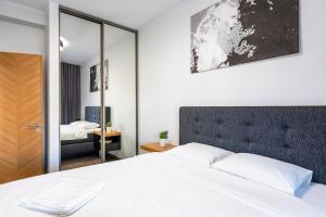 a bedroom with a white bed and a mirror at TartuKodu Fortuuna 23A-2 in Tartu