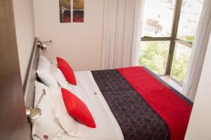a bed that has a red blanket on it at Kube Apartments Express in Córdoba