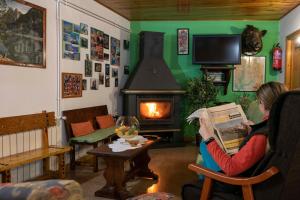 a woman sitting in a chair reading a newspaper in front of a fireplace at Casa Rural Besolí in Areu