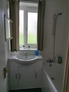 a bathroom with a sink and a window and a tub at Cosy Flat Close To East Dulwich Station in London