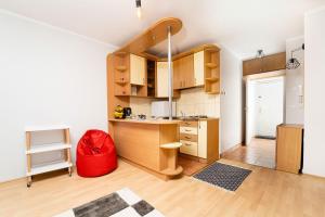 a kitchen with wooden cabinets and a red ottoman at Apartament Kortowski in Olsztyn