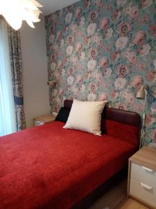 - une chambre avec un lit rouge et un papier peint floral dans l'établissement Balatonboglár - Golden Bridge Apartments, à Balatonboglár