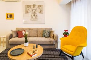 a living room with a couch and a table and a yellow chair at Anemi Apartments in Nafplio