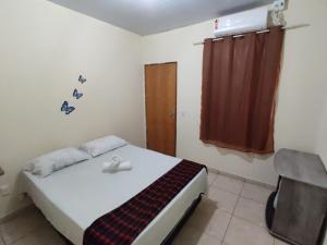 um quarto com uma cama, uma cadeira e uma janela em Pousada do Professor em Pirenópolis