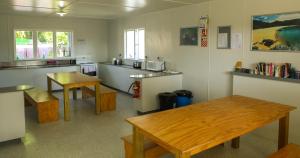 a kitchen with a wooden table and a counter at Marahau Beach Camp in Marahau