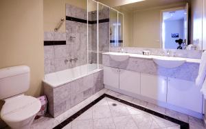 a bathroom with a toilet and a tub and a sink at Flinders Landing Apartments in Melbourne