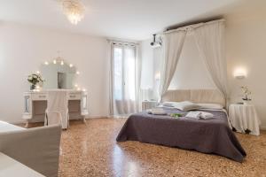a white bedroom with a bed and a mirror at Palazzo DaPonte in Venice