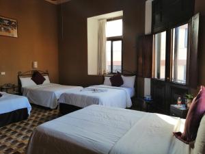 a hotel room with three beds and two windows at Hotel Reforma in Mérida +90 photos