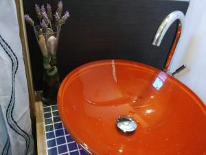 an orange sink in a bathroom with a vase of flowers at Mar y Cerros in Piriápolis