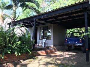 a house with a blue truck parked under a porch at Umlalazi Cottage in Mtunzini