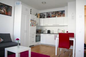 a kitchen and living room with white cabinets and red chairs at Trendy Danube Apartment - Close to UN in Vienna