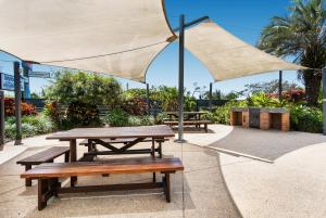 a patio area with a table, chairs, and umbrellas at Mylos Holiday Apartments in Alexandra Headland