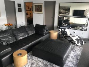 a living room with a black leather couch and ottoman at Residence du Lac in Queenstown