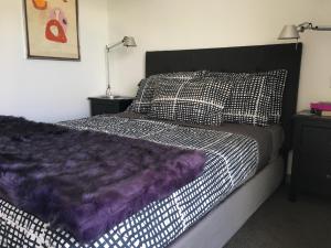 a bedroom with a bed with a purple comforter at Residence du Lac - 2 Bedroom apartment in Queenstown +30 photos