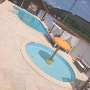 two swimming pools with umbrellas on a patio at Pensiunea Oana ☆☆☆ in Şoimuş