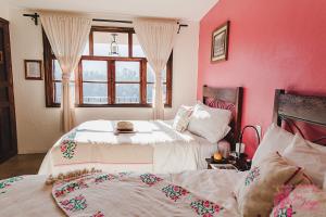 two beds in a room with pink walls and a window at Hotel San Jorge in Tlatlauquitepec