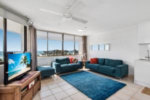 a living room with a couch and a tv at Mylos Holiday Apartments in Alexandra Headland