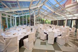 un salón de banquetes con mesas y sillas blancas y techos de cristal en Hotel Harrison Etxea, en Amorebieta-Etxano