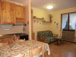 a kitchen and living room with a table and a couch at Appartamento Belvedere in Molina di Ledro