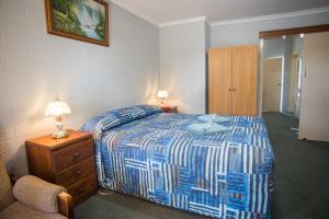 Schlafzimmer mit einem Bett mit einer blauen und weißen Bettdecke in der Unterkunft Murray Bridge Motor Inn in Murray Bridge