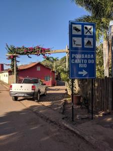 una señal en el lateral de una calle con un coche en Pousada Canto do Rio, en Três Marias