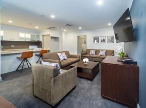 a living room with two couches and a kitchen at Hyde Park Inn in Sydney