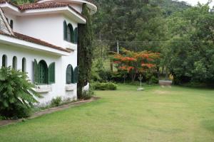 einen Hof neben einem weißen Haus mit einem Baum in der Unterkunft Chácara Dona Eulália in Monte Alegre do Sul