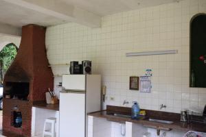 a kitchen with a white refrigerator and a tile wall at Chácara Dona Eulália in Monte Alegre do Sul