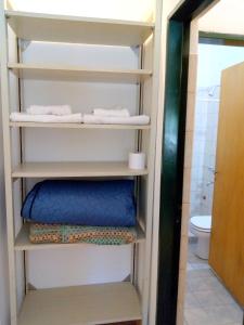 a bathroom with a toilet and a shelf with towels at B&B Garden Atelier in La Cumbre