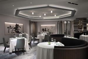 a restaurant with white tables and chairs and a large mirror at The Landis Taipei in Taipei
