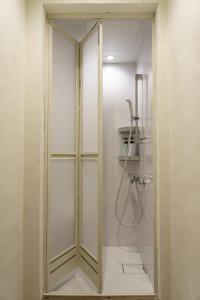 y baño con ducha y puerta de cristal. en ゲストハウス さんかくワサビ en Saiki