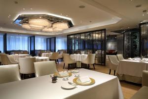 a dining room with white tables and chairs at The Landis Taipei in Taipei