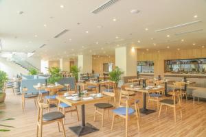 a restaurant with wooden tables and blue chairs at Carinae Danang Hotel in Danang