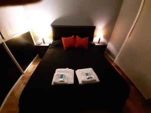 1 dormitorio con 1 cama negra y 2 toallas en Caballito Sun en Buenos Aires