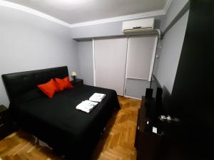 1 dormitorio con cama negra y almohadas de color naranja en Caballito Sun en Buenos Aires