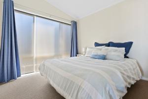 sypialnia z dużym łóżkiem z niebieskimi zasłonami w obiekcie Serenity by the Sea w mieście Tura Beach