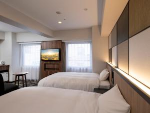 a hotel room with two beds and a flat screen tv at Takasaki Washington Hotel Plaza in Takasaki