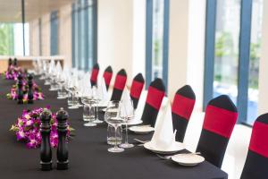 a long table with red and black chairs and wine glasses at Carinae Danang Hotel in Danang +65 photos
